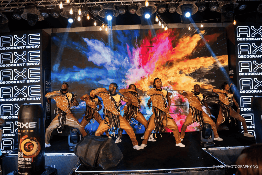 A dynamic stage performance at the AXE Dark Temptation Influencer Soirée, featuring energetic dancers in coordinated outfits against a stunning digital backdrop of vibrant colors. The event highlights brand activation, immersive consumer experiences, and the power of influencer marketing in creating memorable brand engagements.